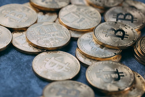 青い背景に散らばる金色のビットコインメダル