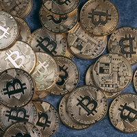 青い背景に散らばった金色のビットコインコインの写真