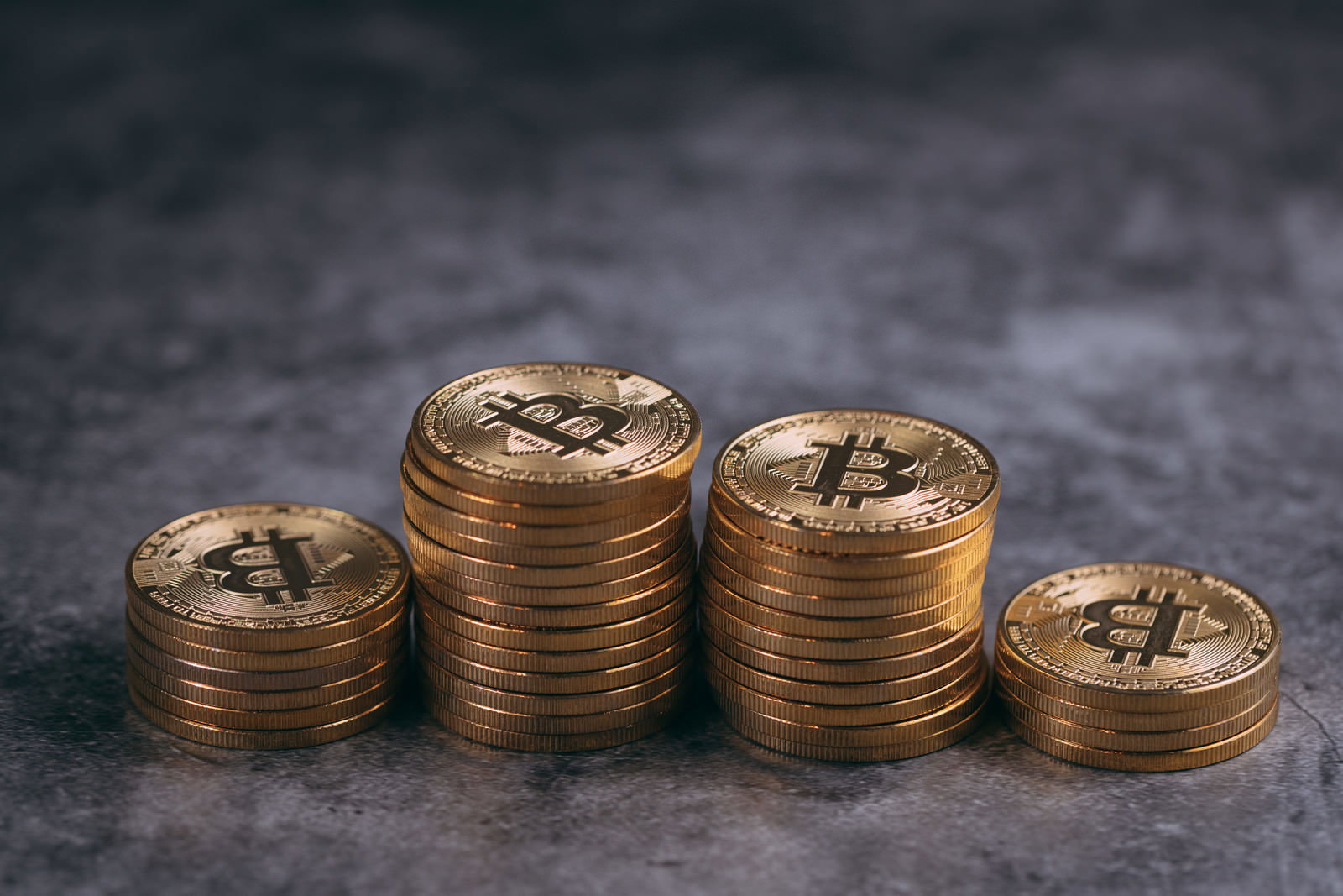 金色のビットコインが4つの山に積み重ねられている