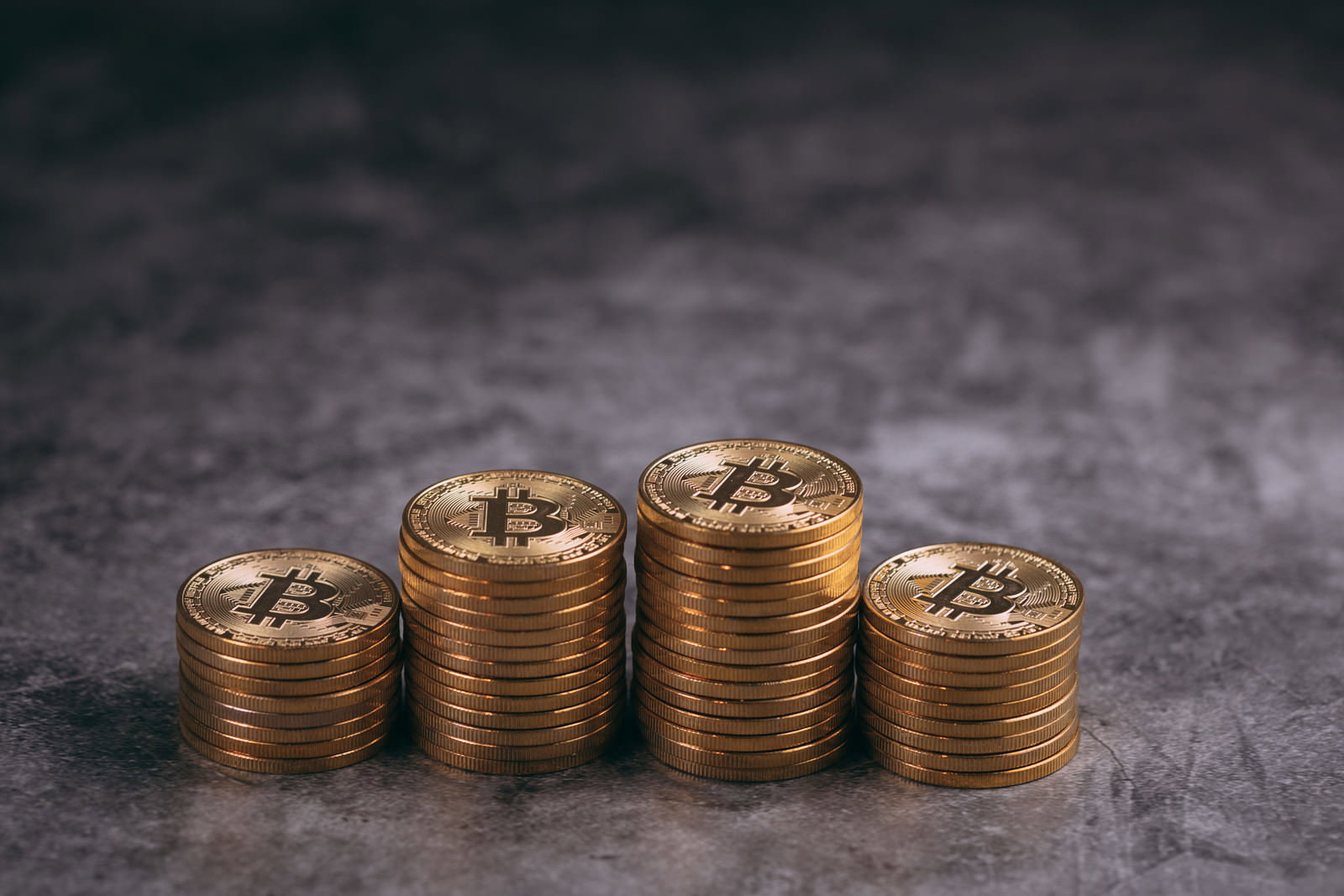 暗い背景に4つの異なる高さに積み重ねられた金色のコイン