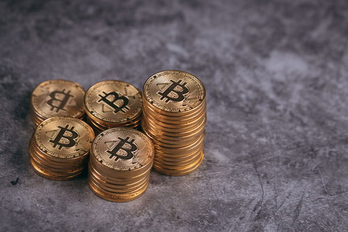 金色に輝く複数のビットコインを一山高く積み上げた様子