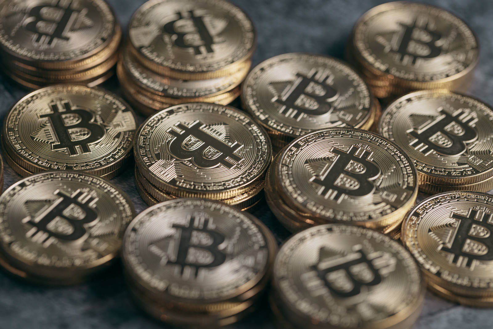 金色に輝くビットコインのロゴが印刻された複数の金貨が積み重なっている