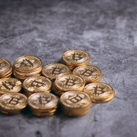 グレー背景に散らばるビットコインの金貨、仮想通貨投資の写真