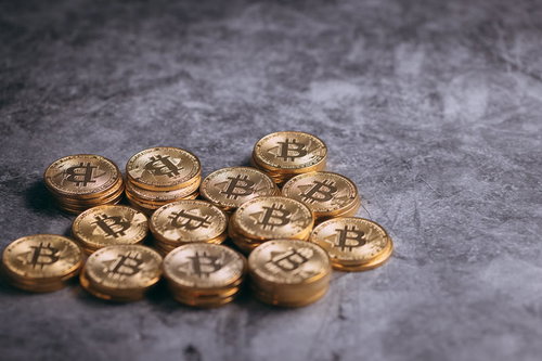 グレー背景に散らばるビットコインの金貨、仮想通貨投資
