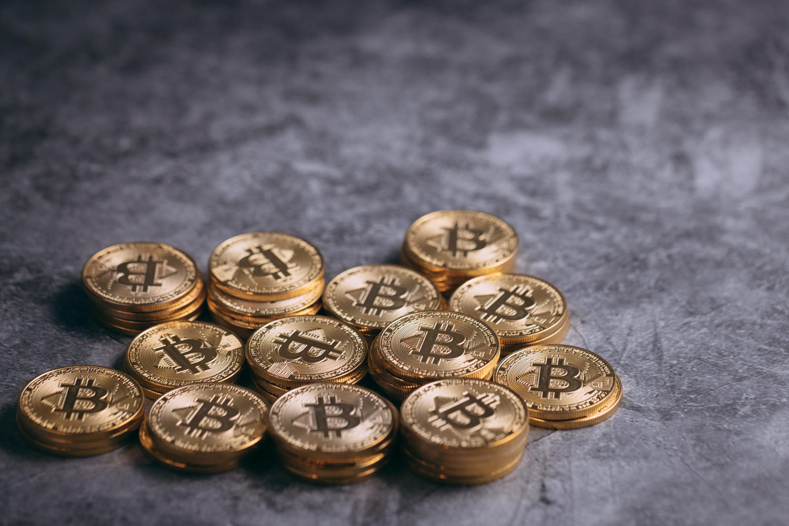 石の表面に並べられたビットコインのロゴが刻印された金色のコイン