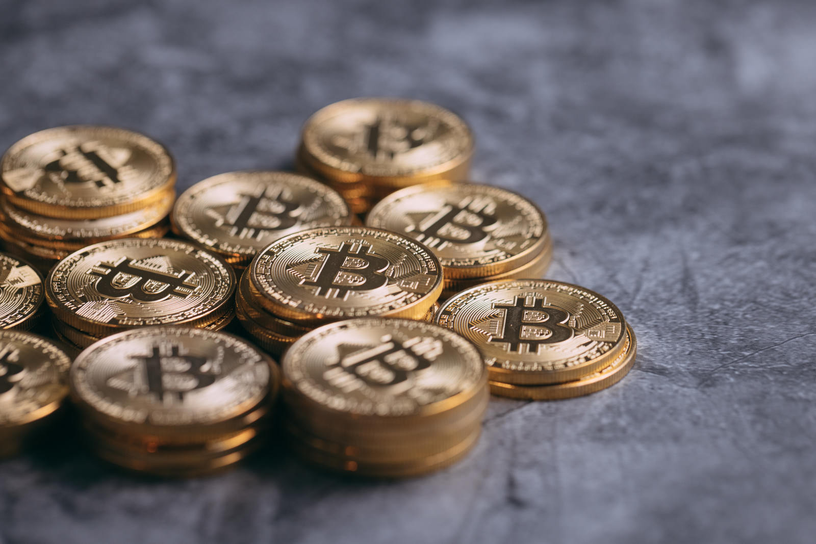 グレーの表面に散らばって配置された金色のビットコインコイン