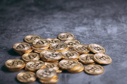 グレーの背景に輝く散らばったビットコインコイン