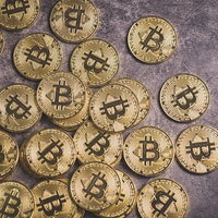 石の背景に散らばる金色のビットコインコインの写真