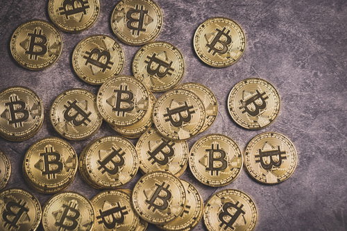 石の背景に散らばる金色のビットコインコイン