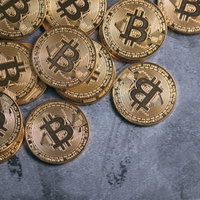 デジタルゴールド、ビットコインコインが青いテーブルに散らばるの写真