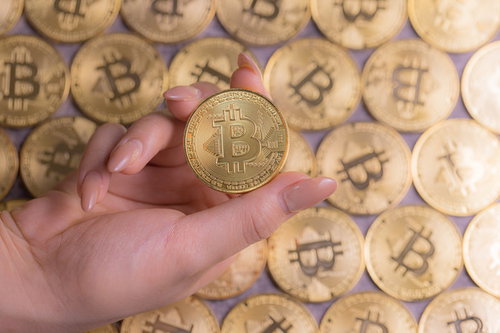 輝くビットコインを手にする女性の右手と指
