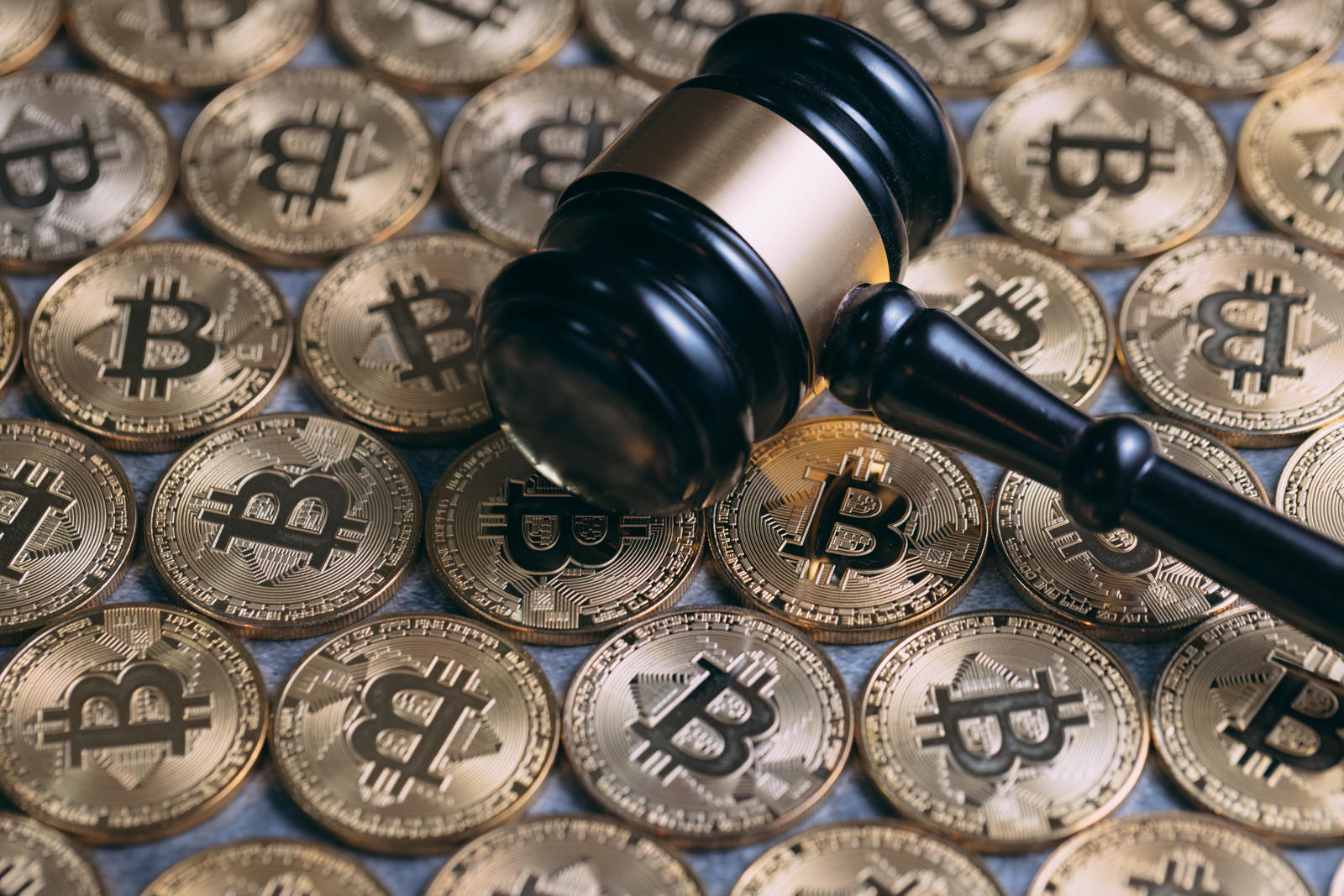 ビットコインのコインと木製の小槌が並んで配置された写真