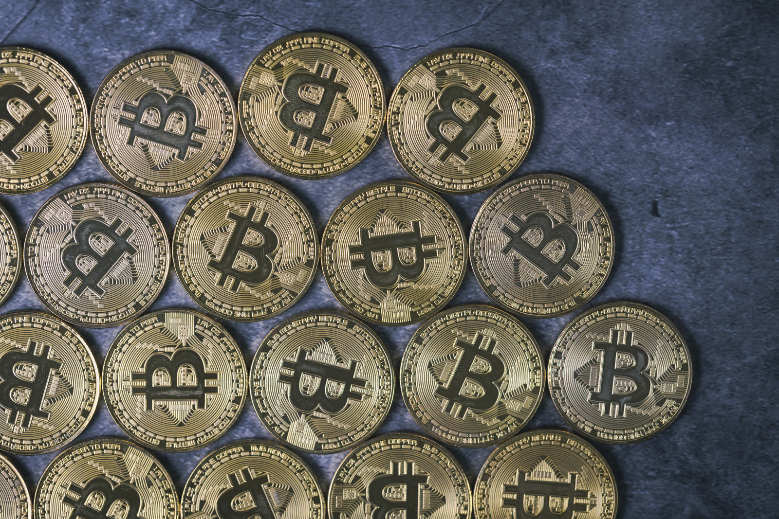 石板の上に格子状に並ぶビットコインのコイン