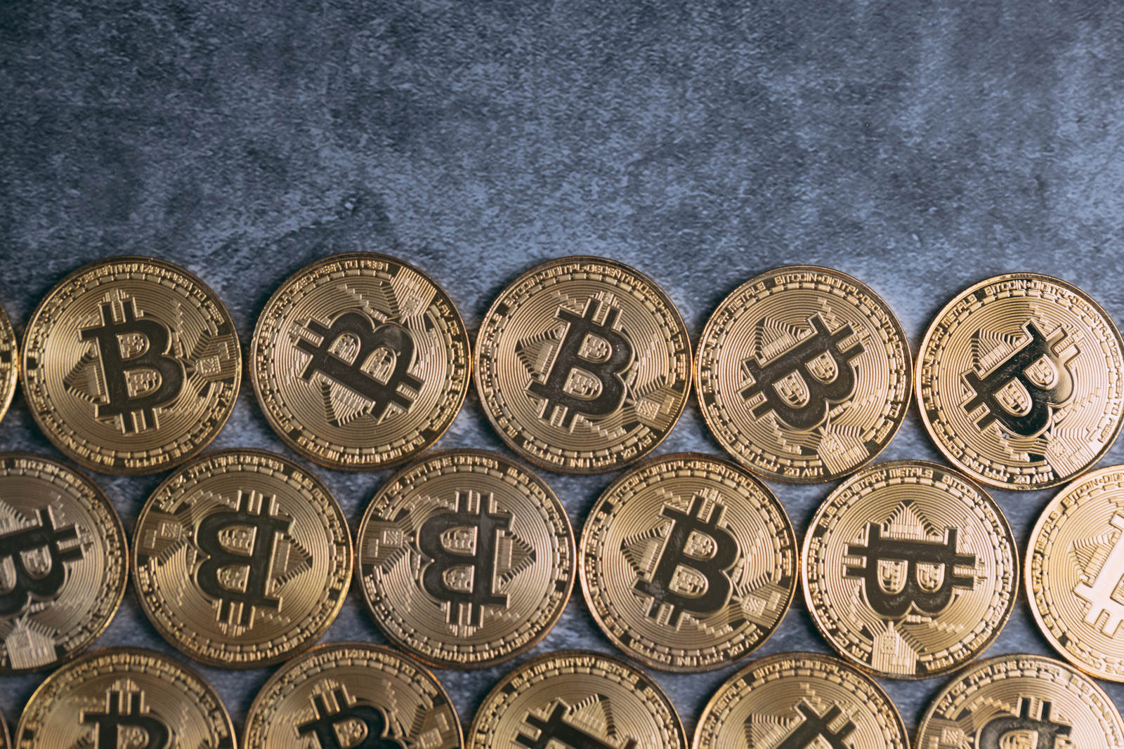 石の表面に並べられたビットコインのロゴが刻印された金色のコイン
