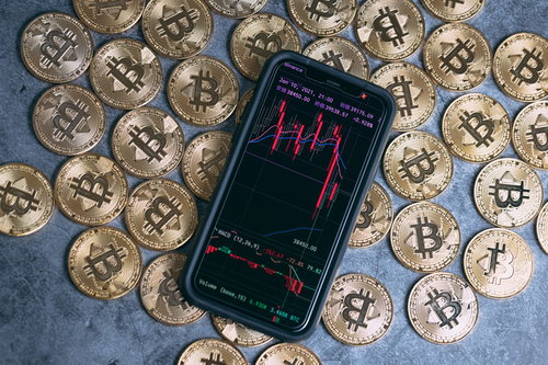 ビットコイン金貨とスマートフォンに表示された大暴落チャート