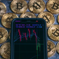スマートフォンのトレード画面に表示された大暴落チャートとビットコインの写真