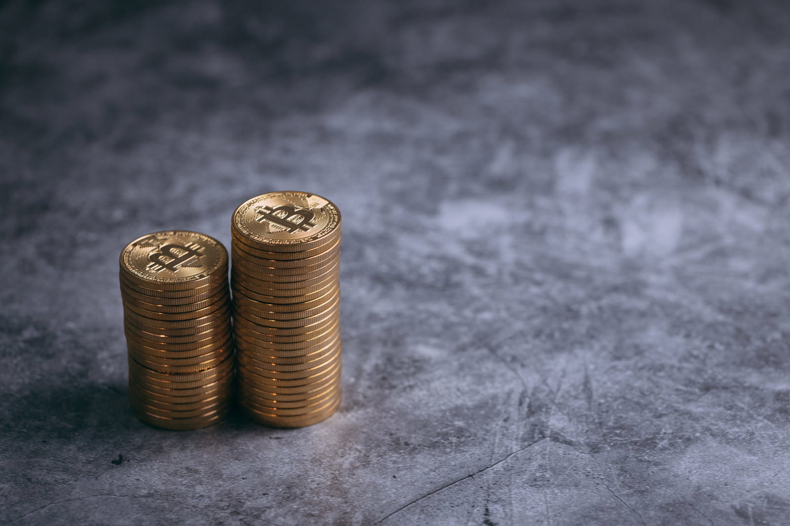 グレーの背景に2つの円柱状に積み重なった金色のコイン