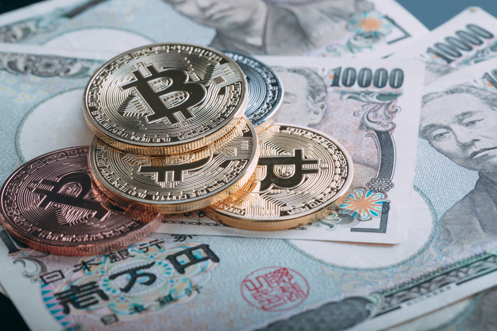 金色のビットコインのコインと一万円札が配置された投資イメージ