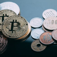 机の上に並べた小銭とゴールドのビットコインの写真