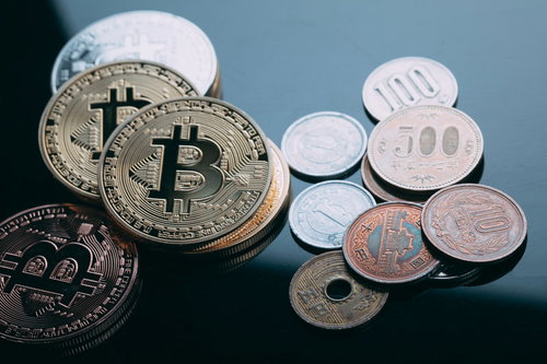 机の上に並べた小銭とゴールドのビットコイン