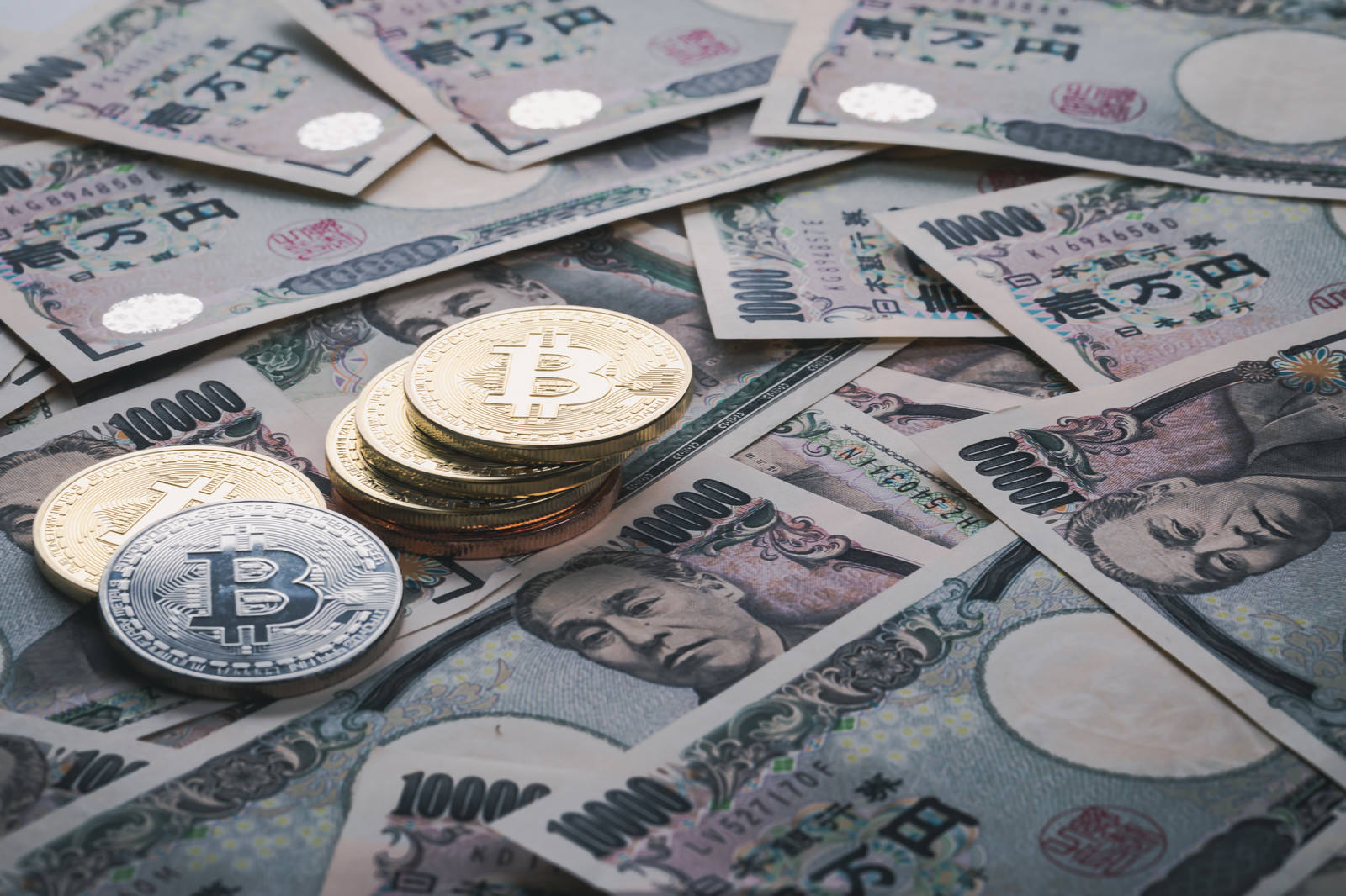 1万円札の上に積まれたビットコインコイン