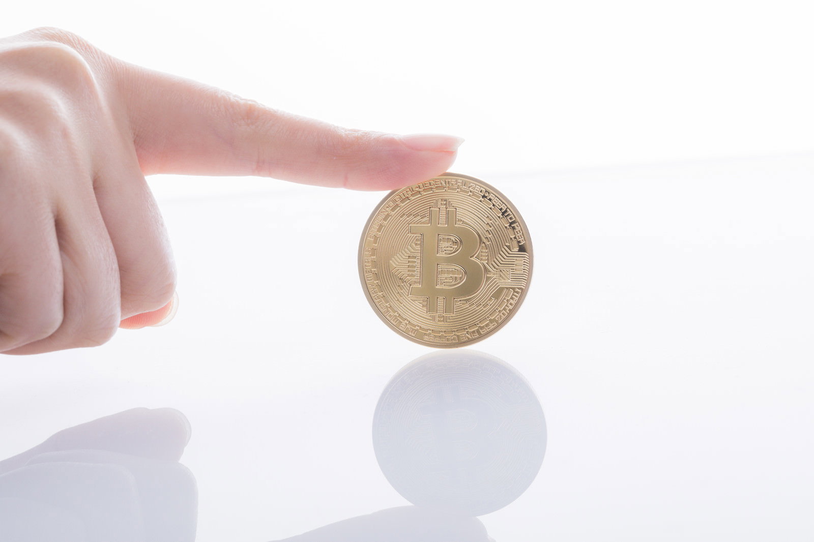 白い背景でビットコインを人差し指で指し示す手