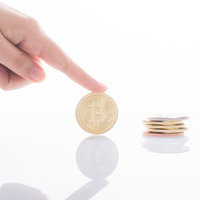 ビットコインを指差す手と積み重ねた金貨の投資の写真