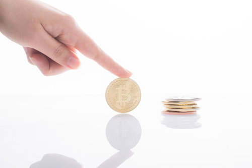 ビットコインを指差す手と積み重ねた金貨の投資