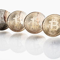 白い背景に並ぶビットコイン4枚の金色のコインの写真