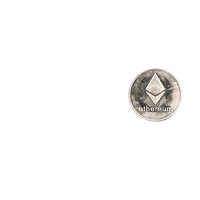 シルバーのイーサリアム（ETH）コイン、白い背景に置かれたデジタル資産の写真