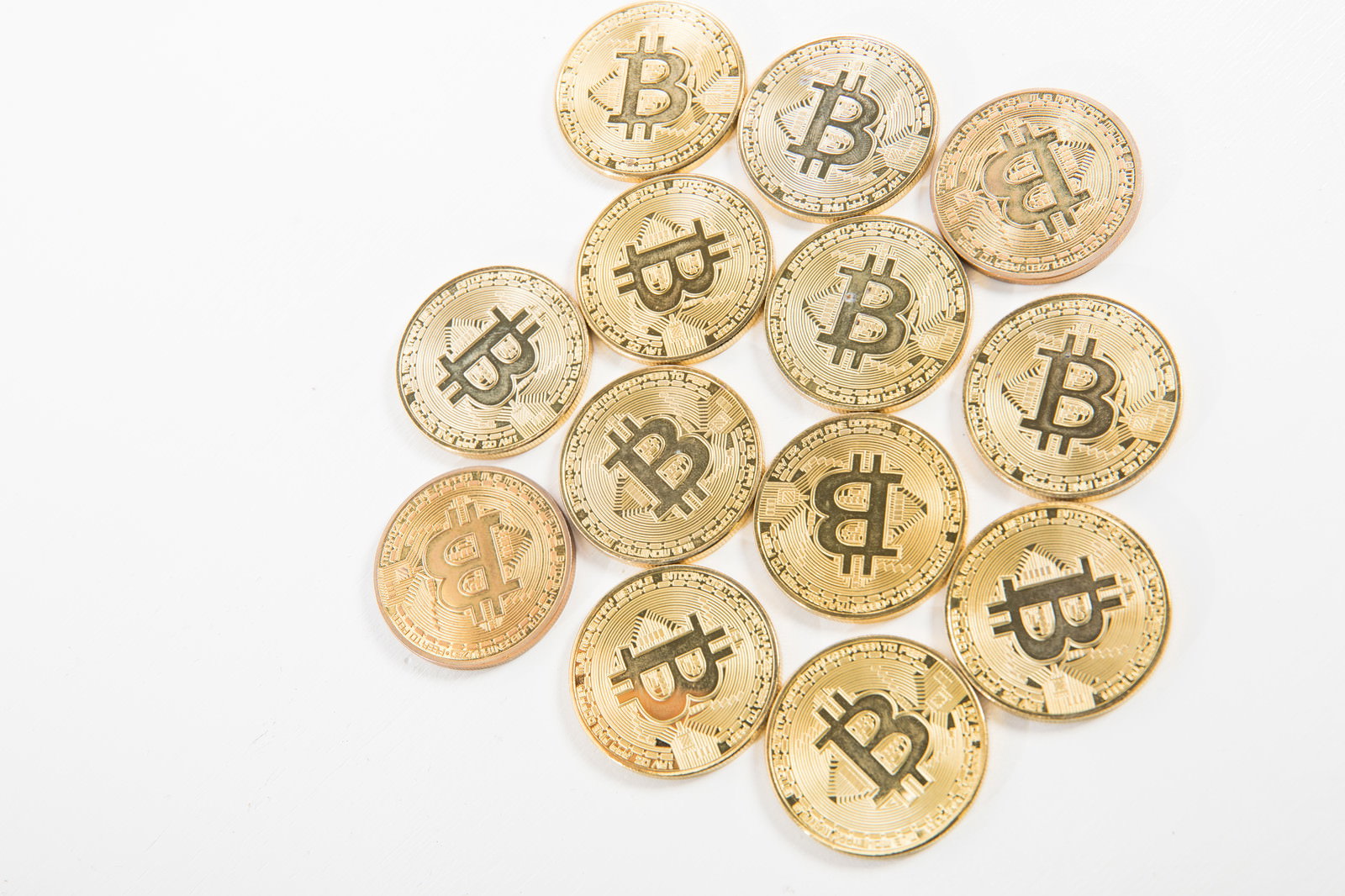 白い背景に金色のビットコインが複数散らばって配置されている