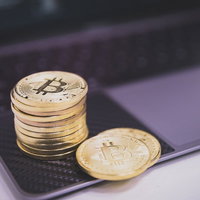 ノートパソコンの上に積み重ねられたビットコインの写真