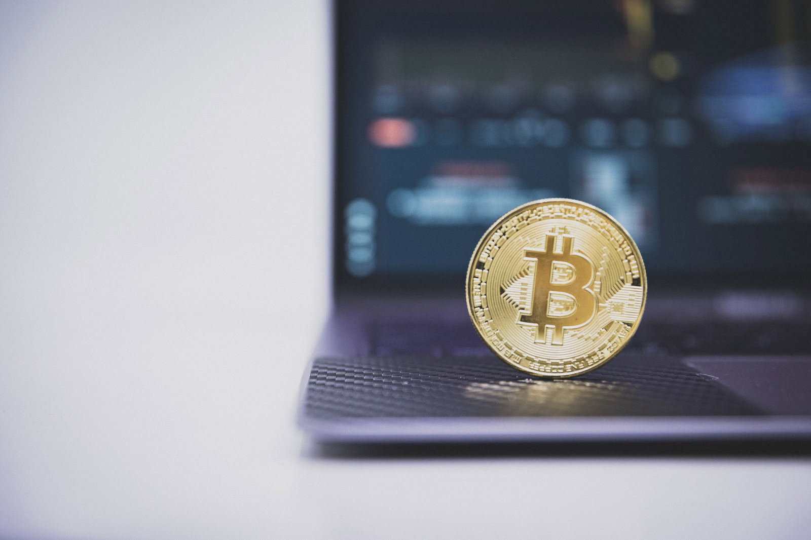 金色のビットコインコインがノートパソコンのキーボード前に置かれている