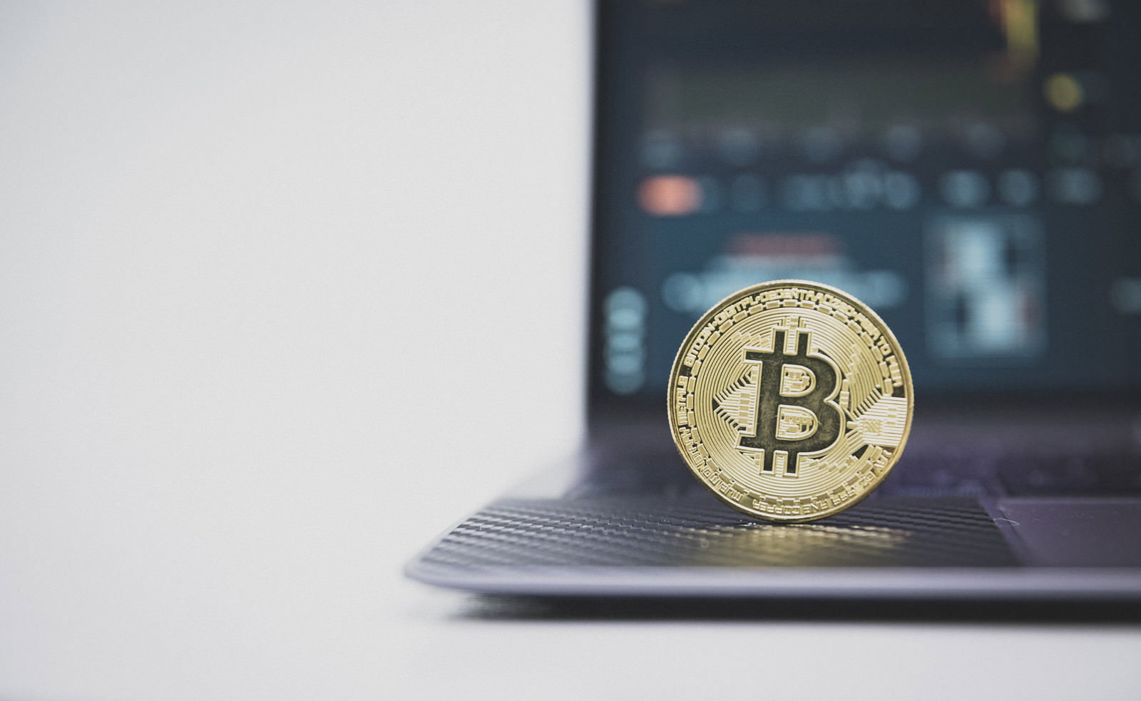 ノートパソコンのキーボード上に置かれた金色のビットコイン