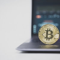 ノートパソコンのキーボード上に置かれたPC上のビットコインの写真