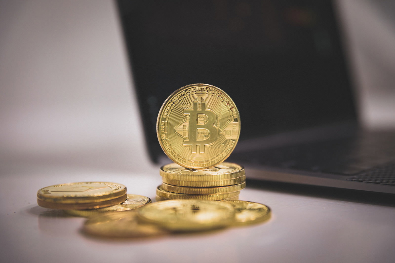 ノートパソコンのキーボード周辺に置かれた金色のビットコインコイン