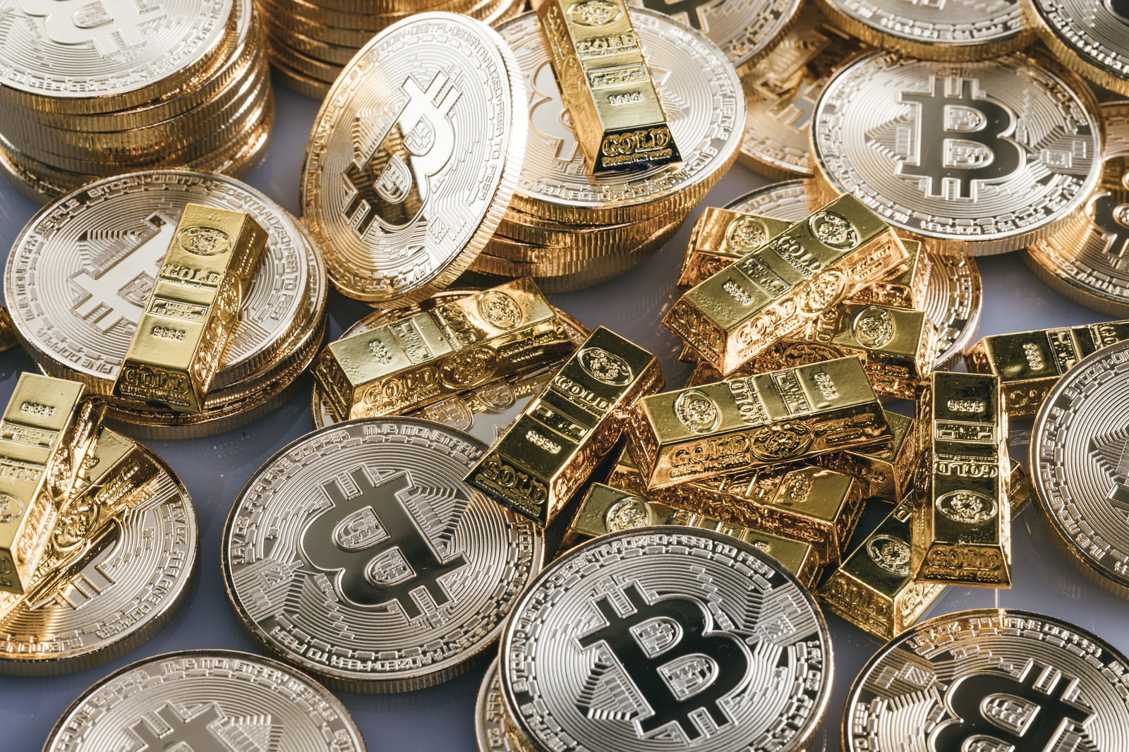 金色に輝く金塊とビットコインのコインが並んで配置されている