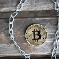 古い木の板に置かれたビットコインとチェーンの写真