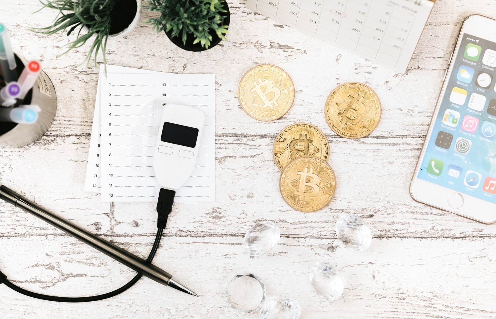 白いテーブルの上のTREZORハードウェアウォレットとビットコイン金貨