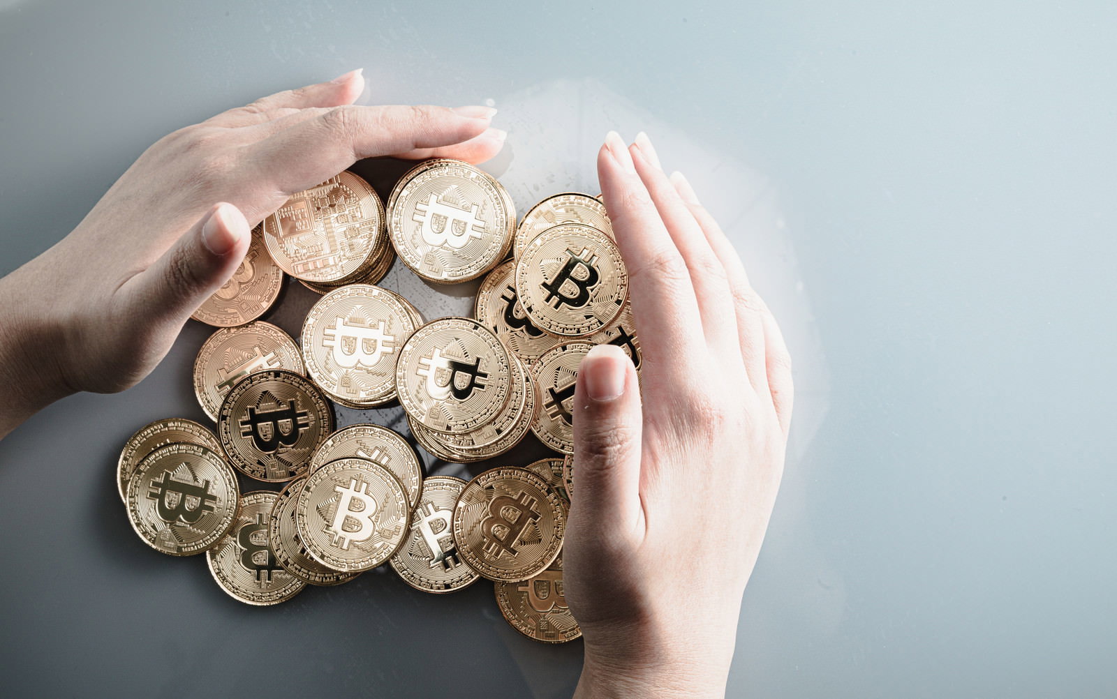 両手で大切にビットコインのコインを包み込んでいる様子