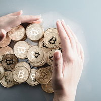 両手でビットコインを守るように包み込む投資の写真