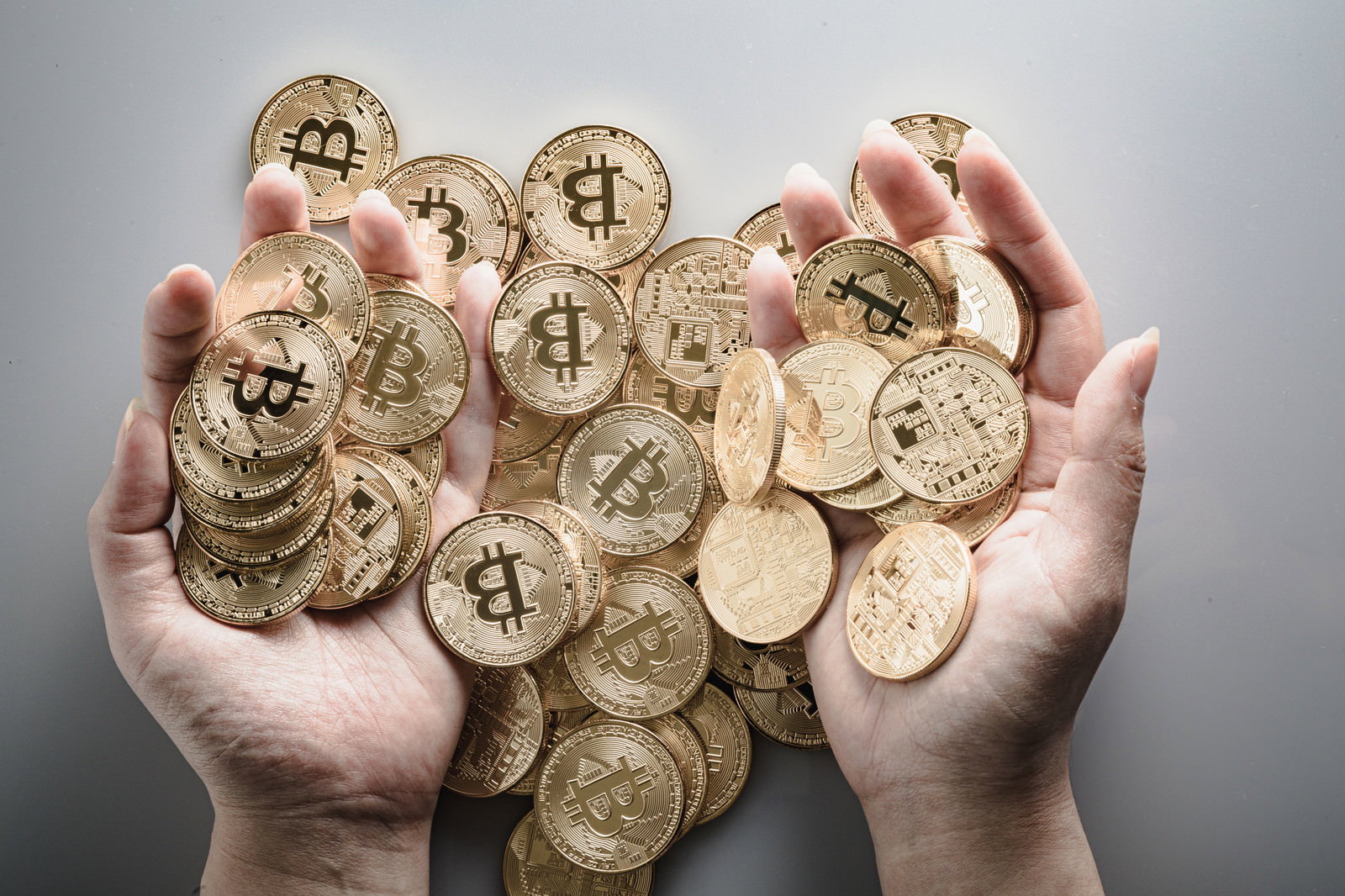 両手いっぱいに金色のビットコインコインを持っている様子