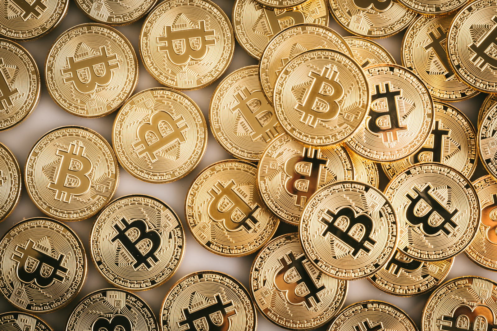 ビットコインのロゴが刻印された金色のコインが積み重なった写真