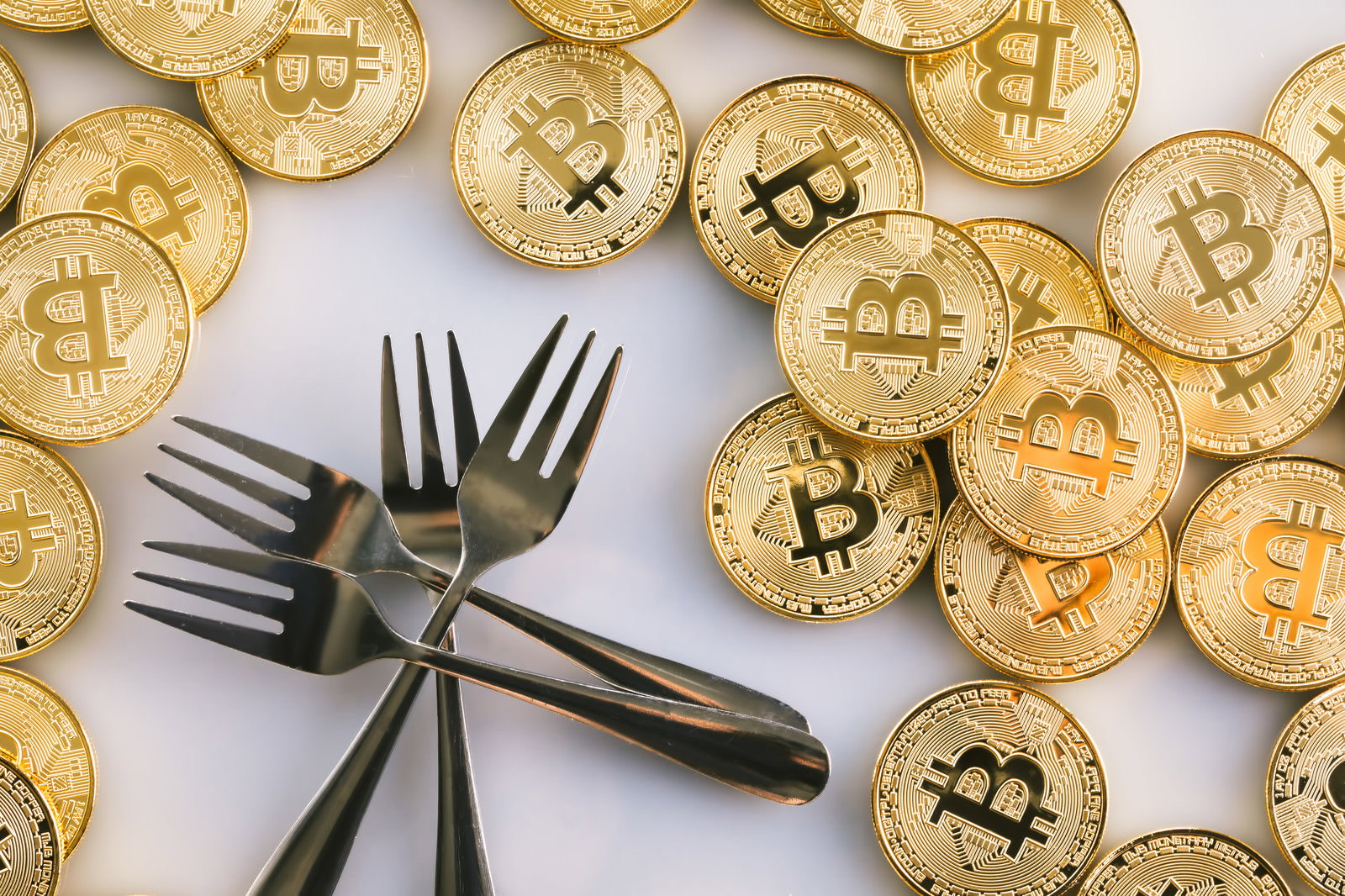 金色のビットコインコインと黒いフォークが並べられた写真