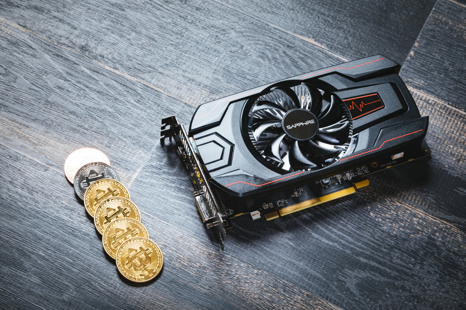 黒い表面に置かれたグラフィックボードと金色のビットコイン