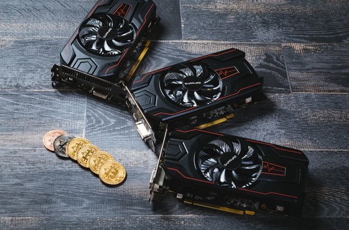 木目調のテーブルに並ぶ複数のグラフィックボードでビットコインをマイニング