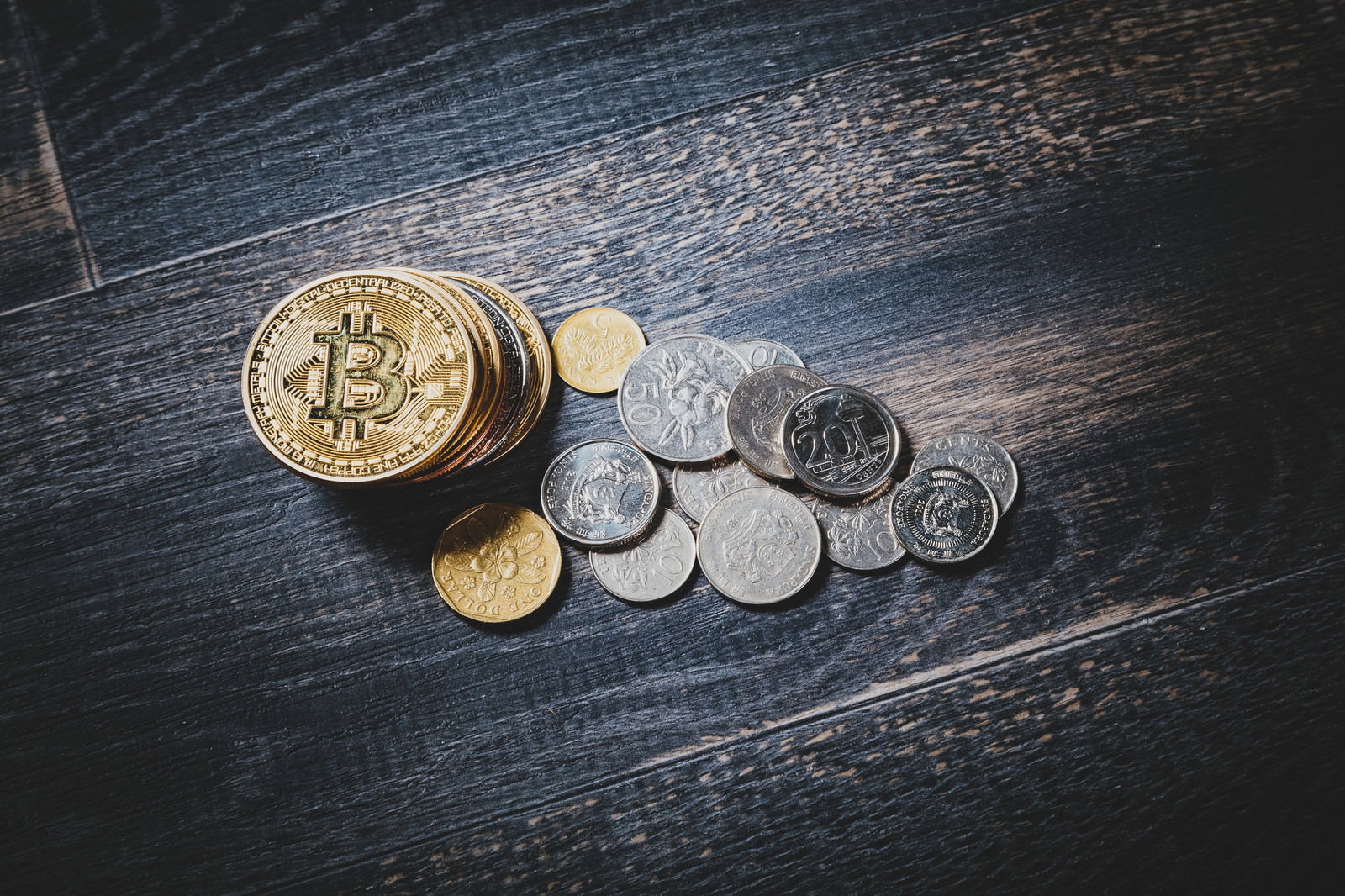 木製テーブルの上に置かれたビットコインとシンガポールドルの硬貨