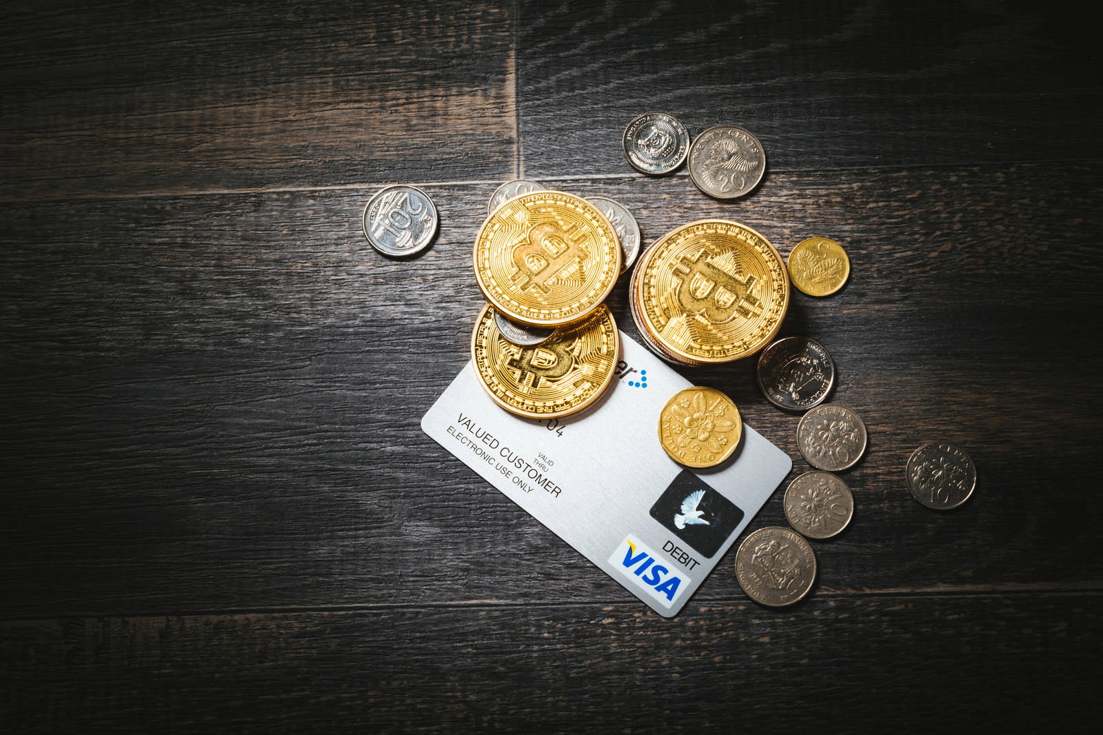 木製テーブルに置かれたビットコインコインと現金、クレジットカード