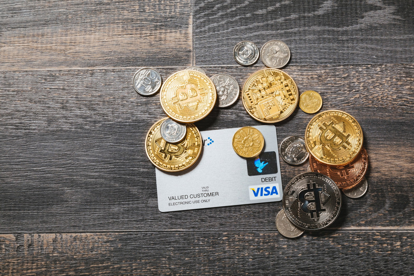 木製テーブルの上に置かれた金色のビットコインコインとVISAクレジットカード