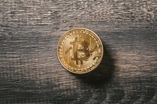 木目のテーブルに置かれたビットコインの金貨